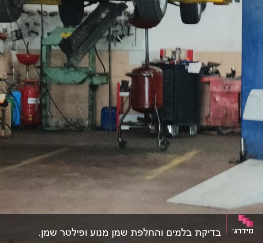 רכב מורם במוסך עם ציוד תחזוקה סביבו